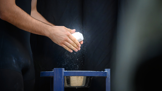 A weightlifter applies chalk to her hands prior to a lift.