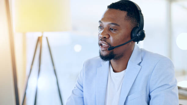 istock Call center, crm and black man talking for telemarketing, tech support or contact us at help desk in office. Customer service, sales agent and serious consultant in communication, advice and business 1765286613