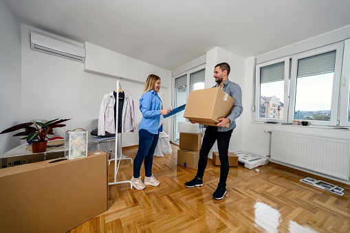 A happy young couple with boxes moving into a new home or apartment. Real estate theme.