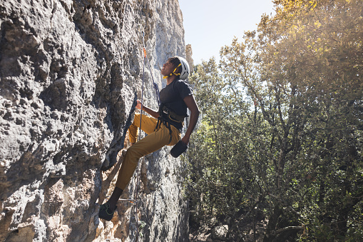 Athletic man climbs a rock with rope and carabiners, lead climbing.  Rock climber concept.