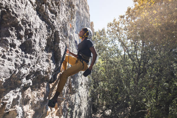 Athletic man climbs a rock with rope and carabiners, lead climbing. stock photo