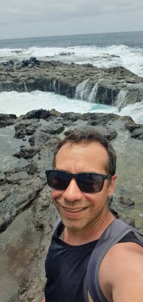 istock young man in sunglasses with the rough sea behind him 1765307466