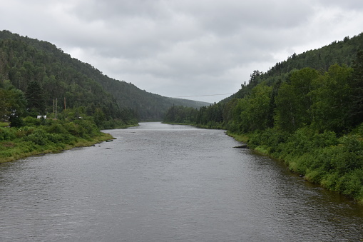 La rivière Matapédia sous un ciel gris, avec des montagnes vertes, en Gaspésie