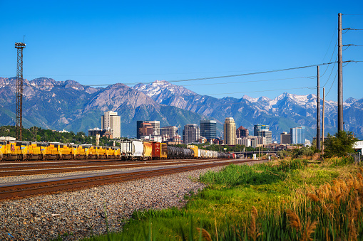 Salt Lake City, Utah, USA - June 11, 2022 : Trains and Union Pacific diesel locomotives lined up in Salt Lake City with city skyline in the background.