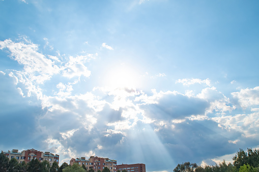 Sky with sun rays over residential buildings. Panorama with empty space for text.