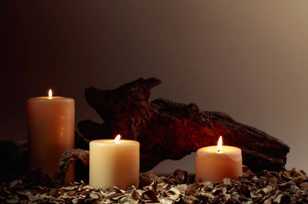 istock Burning candles and old wooden snags on a brown background. 1765342884