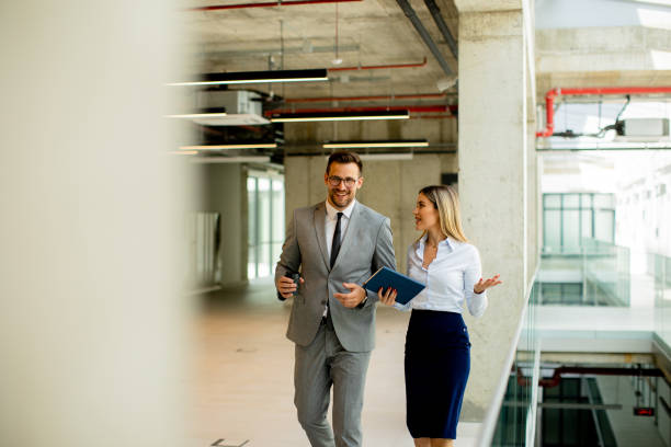 istock Young coworkers walking and talking along corridor in modern office 1765358641