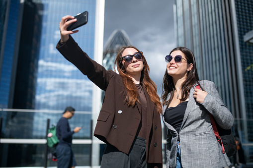 Two young businesswomen taking selfie together in business park.