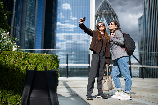 Two young businesswomen taking selfie together in business park.