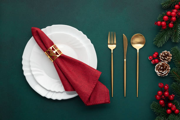 istock Clean plate, gold cutlery. Festive table setting with christmas decorations. Celebration xmas eve: flat arrangement. Red, golden accents. Fir cones on evergreen tree. Holiday banquet, top view. 1765368865