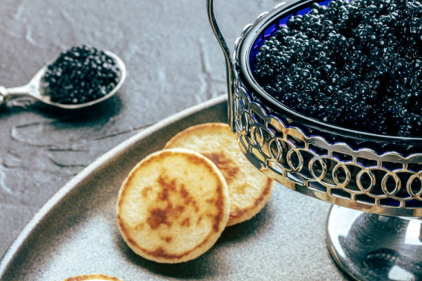istock Vintage caviar dish with black caviar and blinis, a closeup on black 1765374099
