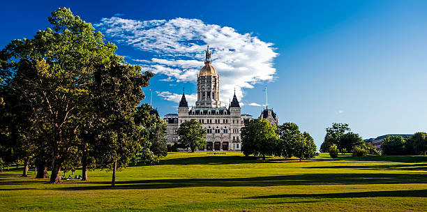 State Capitol and Bushnell Park, Hartford, Connecticut Photo taken early summer evening at Bushnell Park, Hartford, Connecticut. The long shadows indicated sunset is approaching but the state capitol is brightly lit by the setting sun. A group relaxes under the trees. The Legislative Office Building is on the right. the State Capitol Building is viewed here from Bushnell Park. connecticut state capitol building stock pictures, royalty-free photos & images