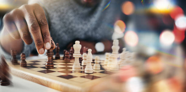 Hand, chess and board game with moving, strategy and choice in competition, problem solving and bokeh. Person, toys and contest with queen, king or check with knowledge, solution or closeup with idea You only win by knowing your opponent's next move chess stock pictures, royalty-free photos & images