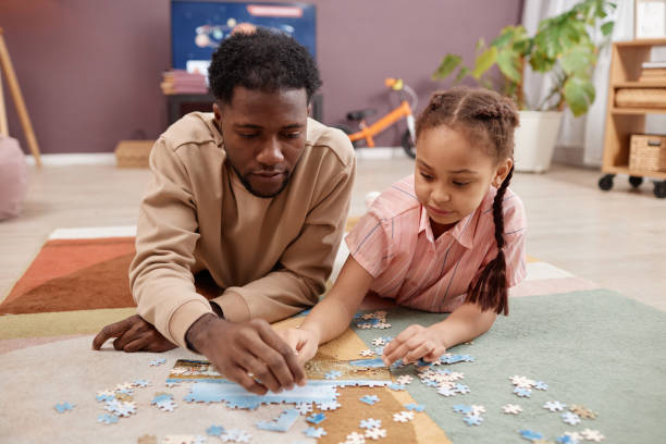 istock Father and daughter solving jigsaw puzzle lying on soft carpet at home 1765380116