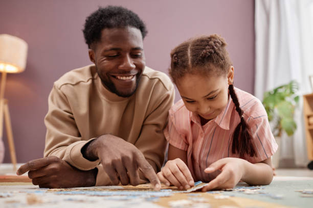 istock Happy Black father solving jigsaw puzzle with little girl 1765380127