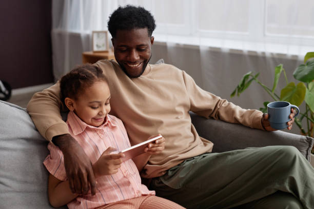 istock Father and daughter at home and using digital tablet 1765380137