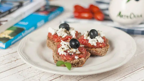 Dakos is a traditional Cretan (Greek) light meal also known as koukouvagia. It consists of soaked dried bread topped with chopped tomatoes and crumbled feta, olives and dried oregano.