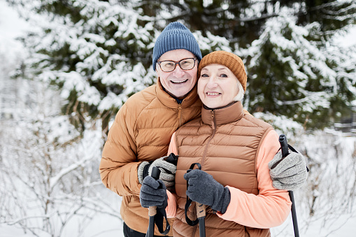 Portrait of happy hugging senior couple ski together on winter
