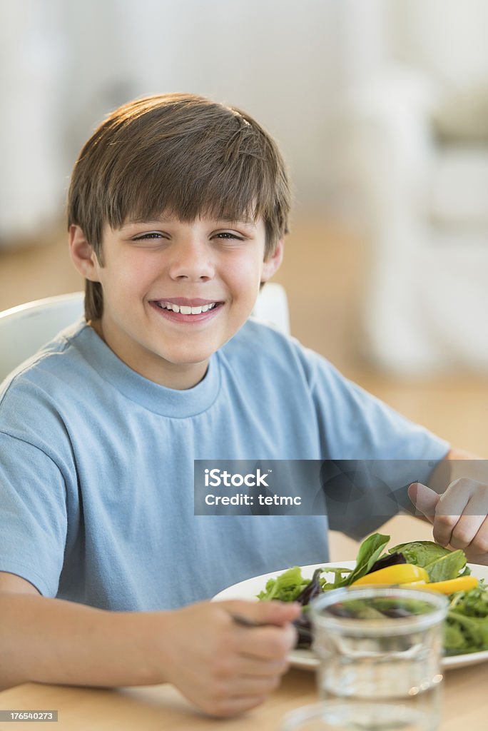 Ragazzo con insalata fresca al tavolo da pranzo - Foto stock royalty-free di 10-11 anni