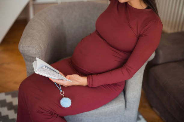Pregnant woman sitting at home and reading a book