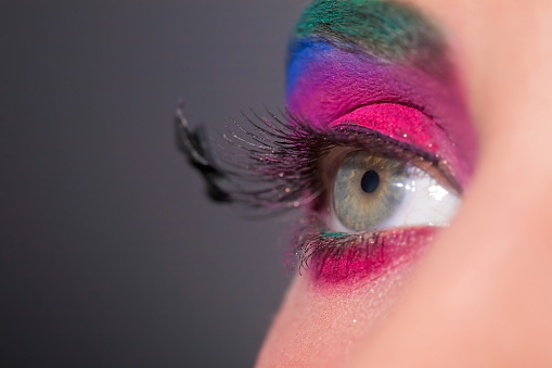 Close up view of female eye with bright multicolored fashion makeup. Holi indian color festival inspired. Studio macro shot.