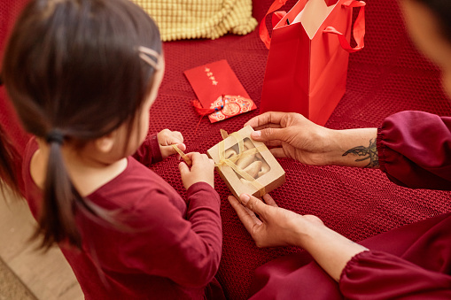 Portrait of happy Asian family celebrating Chinese new year together and giving fortune cookies to child