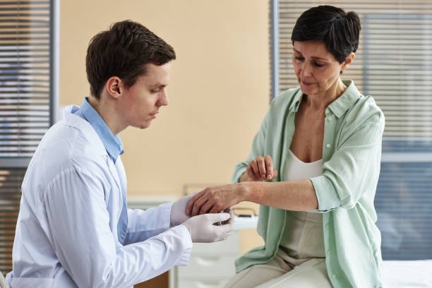 Doctor examining hands of mature woman during consultation in dermatology clinic Side view portrait of doctor examining hands of mature woman during consultation in dermatology clinic, copy space photo psoriasis stock pictures, royalty-free photos & images