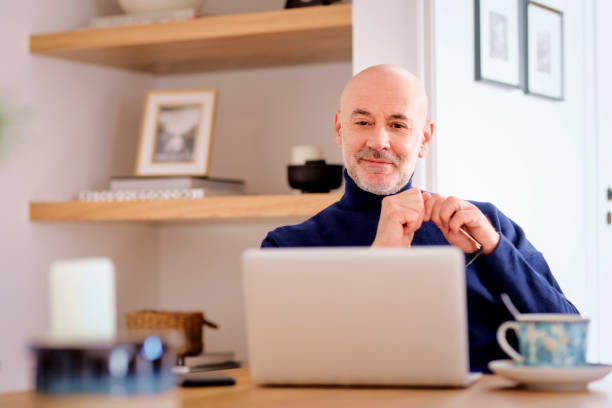 istock Mid aged businessman sitting at home and using laptop for work or having video call 1765433254