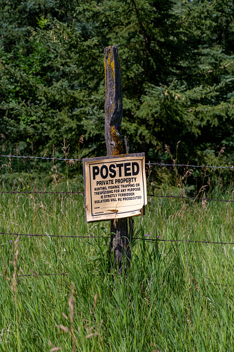 Posted private property sign forbidding hunting, fishing, trapping and trespassing on a wooden fencepost in Minnesota, United States.