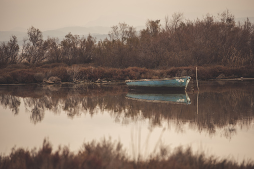 Old, abandoned boat on a lake, its reflection on the water like a mirror. It's autumn