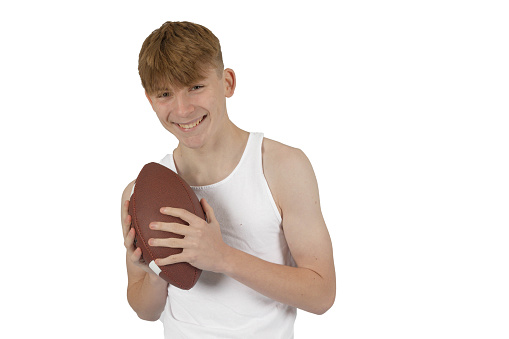 Caucasian teenage boy in a white sleeveless vest holding an American Football