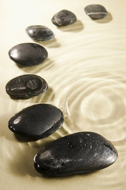 istock Curve of smooth black pebbles in rippled water 176546237