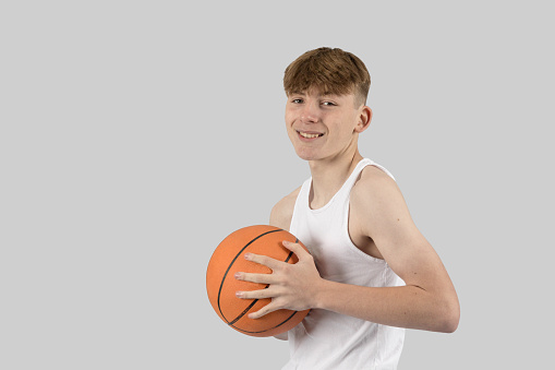 Caucasian teenage boy playing basketball
