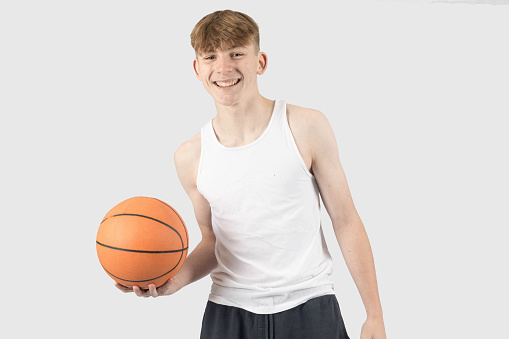 Caucasian teenage boy holding a basketball and smiling