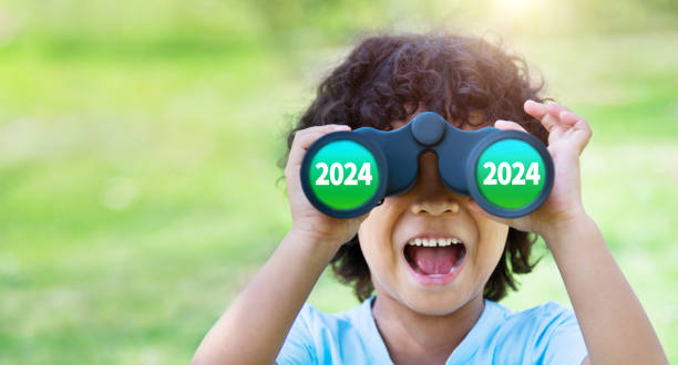 Little boy looking through binocular exciting with new year number 2024