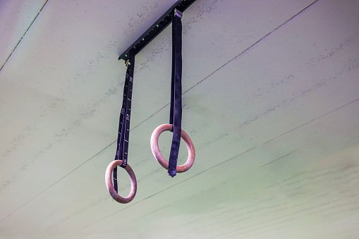 Close up view of gymnastic rings suspended from ceiling in strength training gym. Sweden.