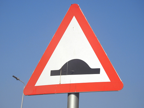 A signboard for Speed bumps ahead, to warn the drivers to be careful and slow down, traffic thresholds, breakers or sleeping policemen, a class of traffic calming devices with vertical deflection, selective focus