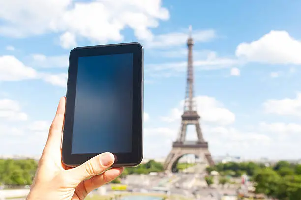 A vertcical Tablet PC against the fantastic Eiffel-Tower in Paris, France. Lots of copy space for whatever in it. Maybe the person is photographing the tower, maybe the person is reading on the tablet. XXL size image.