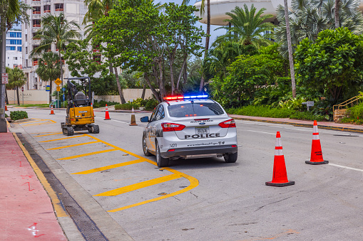 USA. Miami Beach. 10.30.2023. View of police car with its roof lights on standing on one of streets of Miami Beach, which is restricted for traffic because of roadworks.
