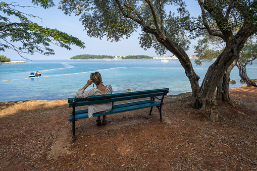 A woman is sitting in a park by the sea