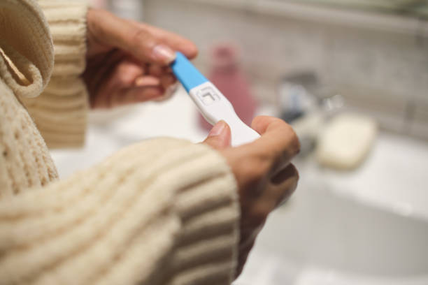 close up shot of white hands holding a pregnancy test in the bathroom side view detail of a latino young woman with a pregnancy test on her hands waiting for the results women satisfaction decisions cheerful stock pictures, royalty-free photos & images