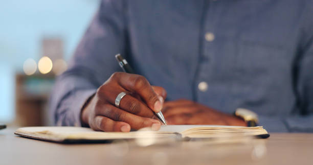 istock Businessman, writing and book for schedule planning, ideas or brainstorming strategy on table at office. Closeup of male person, hands or employee taking notes for project plan or agenda at workplace 1765546966