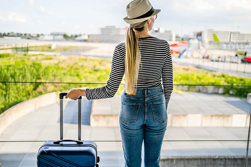 Young woman with her luggage waiting for a flight at the airport