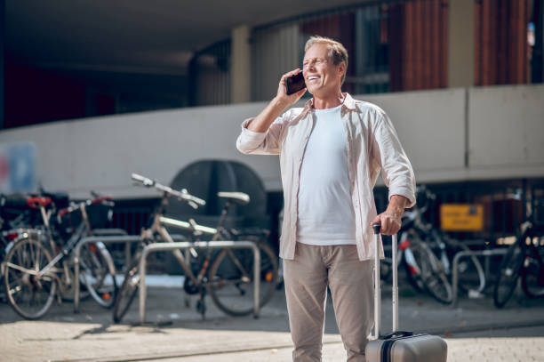 istock Mobile call. Smiling man talking on cellphone with his suitcase in hands. 1765582377