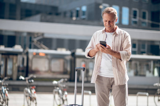 istock Smiling man using mobile phone in city street. 1765582387