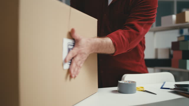 Warehouse worker putting fragile handle with care sticker on a box for delivery