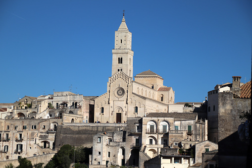 Matera, Basilicata, Italy - 29 october 2023: The Cathedral of the Madonna della Bruna, in Apulian Romanesque style, was built in the 13th century on the highest spur of the Civita that divides the two Sassi, on the area of ​​the ancient Benedictine monastery of Sant'Eustachio, one of the two patron saints of the city. On the outside, note the sixteen-ray rose window and the 52 meter high bell tower; Inside, noteworthy are a Byzantine fresco of the Madonna della Bruna, a sixteenth-century nativity scene by the sculptor Altobello Persio and a fresco depicting the Final Judgement.