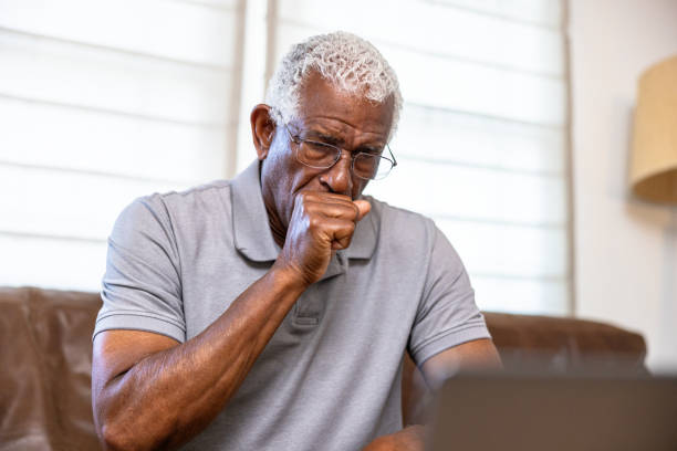 Senior black man coughing Senior black man on telemedicine call with doctor on laptop computer voip cough stock pictures, royalty-free photos & images