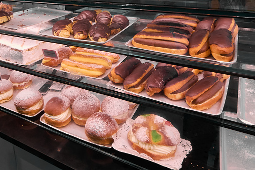 A pastry display case full of cakes and sweets of different colors and flavors, from cupcakes to cakes, including breads and loaves. An appetizing and tempting image for baking lovers.