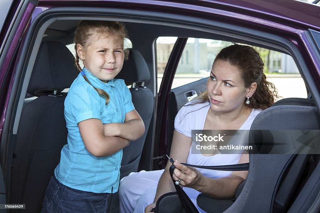 Madre intentando hacer girl por niño asiento de seguridad - Foto de stock de Niño libre de derechos
